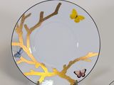 a plate with a gold tree and a butterfly on it