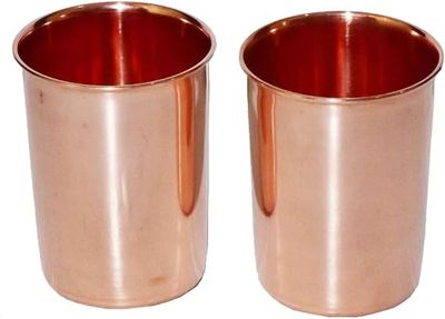 deux tasses en cuivre sont posées l'une à côté de l'autre sur une surface blanche