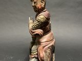 statue of a man sitting on a rock with a bird in his hand