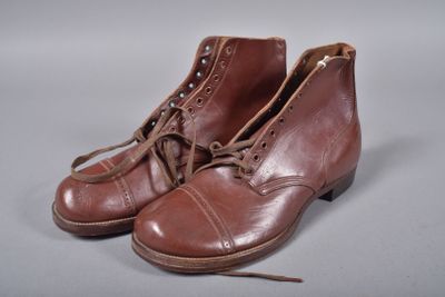 une paire de bottes en cuir marron à lacets posées sur une surface grise