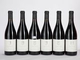 six bouteilles de vin sont alignées sur une table
