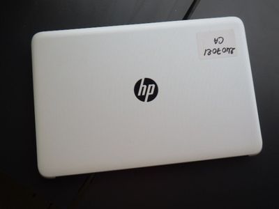 un ordinateur portable blanc, sur lequel est collé un autocollant, posé sur une table
