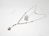 un gros plan d'un collier posé sur une surface blanche, muni d'une étiquette
