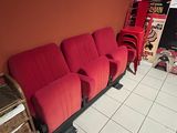 a red couch in the corner of a room with posters on the wall