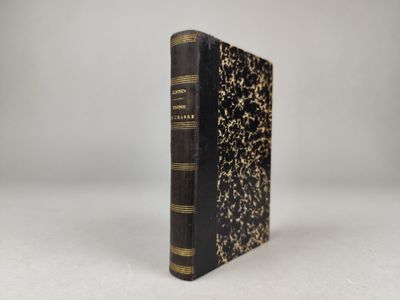 un livre noir et or posé sur une table blanche