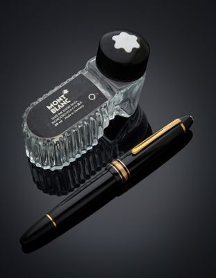 un stylo en forme de pomme et une bouteille en verre avec un bouchon noir