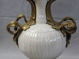 a white and gold vase on a stand on a gray background