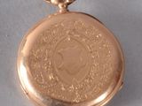 a small gold pocket watch with a chain around it
