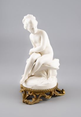 une statue blanche représentant une femme assise sur une table