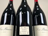three bottles of red wine are lined up on a table