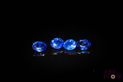 un ensemble de trois saphirs bleus posés sur une surface noire