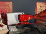 a red guitar case sitting next to a pair of scissors and a pair of scissors