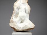une sculpture en marbre blanc représentant la tête d'une femme, posée sur un socle en marbre