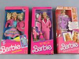 three barbie dolls are in their boxes on a gray surface