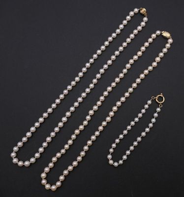 un collier de perles blanches avec un fermoir en or sur fond noir