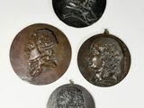 three bronze medallions of a man and a woman on a white surface