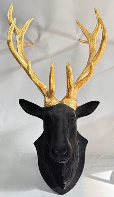 a black deer head with gold antlers on it ' s head