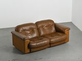 a brown leather couch sitting in a corner of a room
