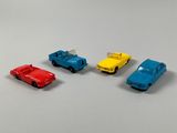 four toy cars are lined up in a row on a white surface