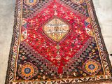 un tapis oriental posé à même le sol dans une pièce où se trouve une chaise