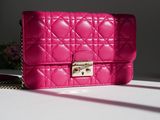 pink quilted purse on a white table with a pink flower in the background