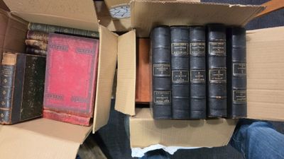 de nombreux livres dans une boîte en carton posée sur le sol