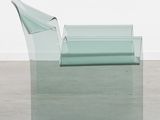 a glass chair that is sitting on a concrete floor