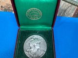 a silver medal in a green box on a blue table