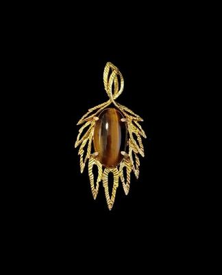 un pendentif en or orné d'une pierre « œil-de-tigre » entourée de feuilles