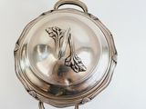 a silver plate with a flower on it on a white surface