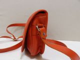 an orange purse on a white table with a strap around it