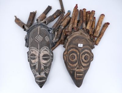Deux masques en bois sont posés l'un à côté de l'autre sur une surface blanche