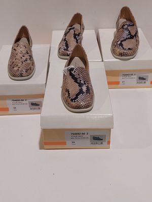 Quatre paires de chaussures sont exposées sur une surface blanche