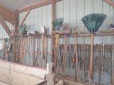 many brooms hanging on the wall of a shed