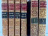 six vieux livres sont alignés sur une surface blanche