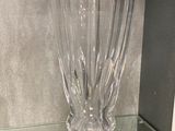 un vase en verre posé sur une étagère en verre dans une pièce