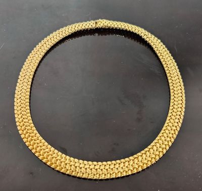 un collier à chaîne en or muni d'un fermoir, posé sur un fond noir