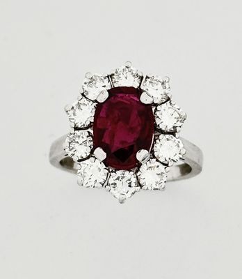 a close up of a ring with a red stone surrounded by white diamonds