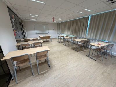tables and chairs in a classroom with a flat screen tv on the wall