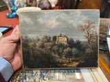 Quelqu'un tient sur une table un tableau représentant un château.