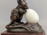 statue of a mouse with an egg on a rock
