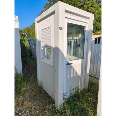 des toilettes portables blanches posées dans l'herbe, près d'une clôture