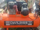 un compresseur d'air orange posé sur un tas de vieilleries