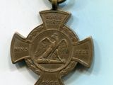 une vieille médaille en bronze sur laquelle figure une croix, posée sur un fond blanc