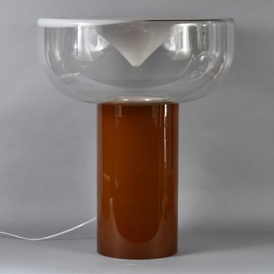 an orange table lamp with a clear glass shade on top of it