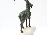 statue of a goat standing on a rock on a white surface