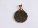 a close up of a small bronze pendant on a white surface