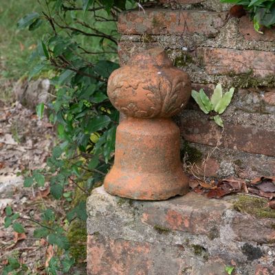 un vase en pierre posé au sommet d'un mur de briques
