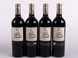 quatre bouteilles de vin sont alignées sur une surface blanche
