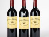 trois bouteilles de vin rouge posées l'une à côté de l'autre sur une surface blanche